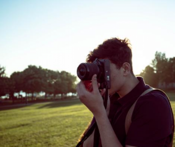 młody człowiek robi zdjęcie do konkursu fotograficznego, w tle zieleń